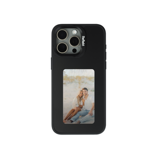 Reflekt™ black E-Ink smart case for iPhone 15 showing a personalized photo of a couple on the back display.